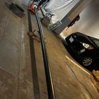 A single long length of black HDPE pipe running the length of a subterranean parking garage toward a crew member working at the fusion machine